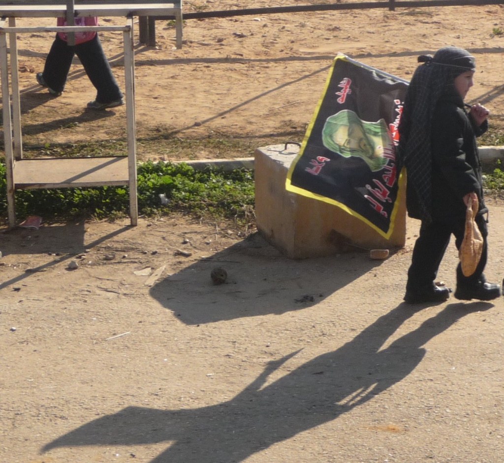 A child carrying a flag with the image of Imam Husayn. --- Un enfant portant un drapeau à l'effigie de l'imam Husayn.