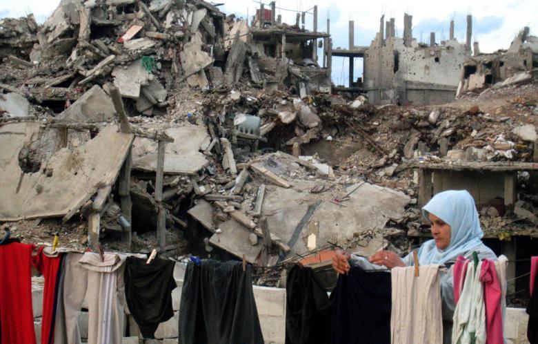 A Palestinian woman hangs laundry at her home in front of destroyed buildings in the devastated Nahr al-Bared Reugee camp in north Lebanon, 07 January 2008. (AFP - Ramzi Haidar)