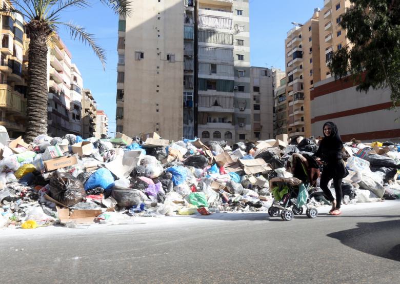 A woman walks past a large pile of garbage bags in Beirut's southern suburbs on January 19, 2014. (Photo: Al-Akhbar / Marwan Bou Haidar)